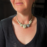 flameworked glass wishing rock necklace in sandstone coloured beads. hand knotted on grey silk cord. shown worn.
