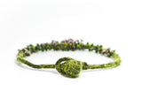 detail view of the closed ball and hoop clasp on a green hand knotted and felted necklace with flameworked mini beads and mini lilac headpins. photo on white background.