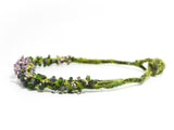 right side detail view of a green hand knotted and felted necklace showing flameworked mini beads and mini lilac headpins. photo on white background.