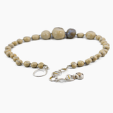 close up of silver and brass extendable clasp on a flameworked glass necklace in a sandstone colour. shown on white background