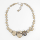 flatlay of sandstone colour wishing rock flameworked glass necklace. hand knotted on grey silk cord with silver and brass clasp. shown on white background
