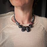flameworked glass necklace in dark charcoal glass. hand knotted on black silk cord and shown worn