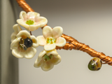 flameworked glass blossom and bee bottom detail on branch of woven copper set in wood frame.