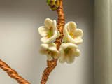 flameworked glass blossom detail on branch of woven copper set in wood frame.