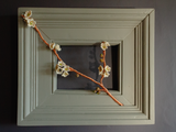 flameworked glass blossoms branch with woven copper in  wood frame on dark background.