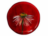  close up image of a round glass coaster showing the top design of the image of echinacea flower on a red background. image is on a white background.