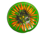 close up image of a round glass coaster showing the top design of the image of a sunflower on a green background. image is on a white background.