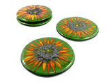 four green glass coasters with images of sunflowers on the top. two individual in the foreground and two stacked on top of each other in the background. image is on a white background.