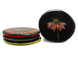 handmade glass coasters stacked three-high on the left side and one showing the top design of the image of an echinacea flower on a black background on the right-hand side. image is on a white background.