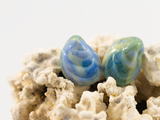 Mussel shell shaped flameworked glass earring studs in colours of blues and yellows reminiscent of a mermaid's tail.