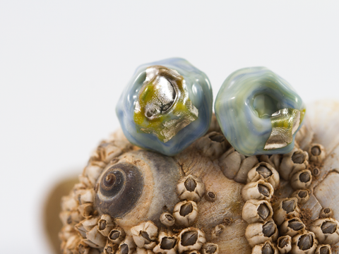 Detail of mini barnacle shaped earring studs with silver foil detail.